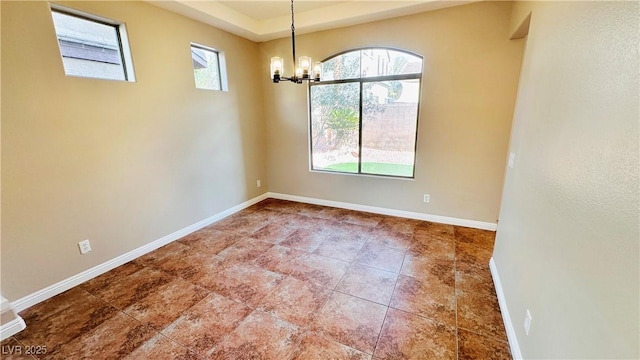 unfurnished room with a healthy amount of sunlight, baseboards, and a chandelier