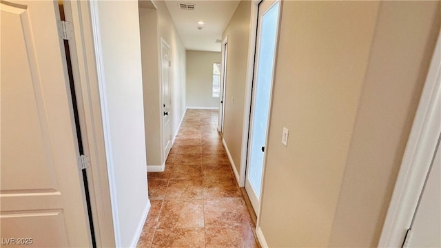 corridor with light tile patterned floors, visible vents, and baseboards