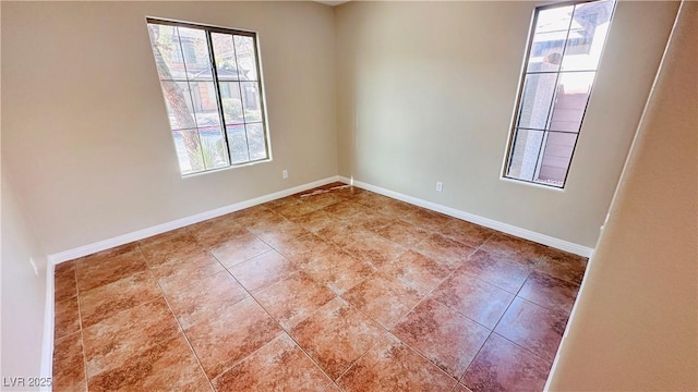 spare room with baseboards and a wealth of natural light