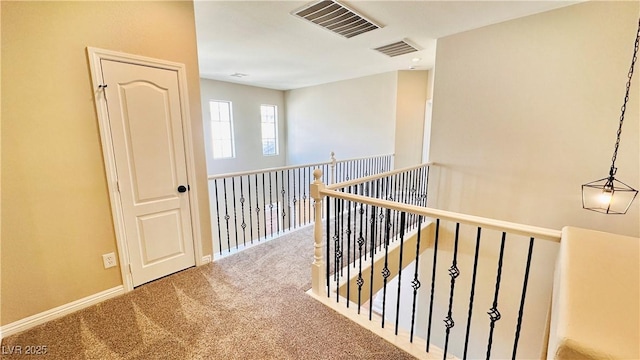 hallway with carpet floors, visible vents, and baseboards