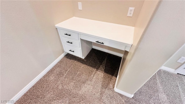 details featuring baseboards, built in study area, and carpet flooring