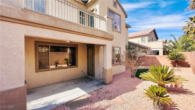 property entrance with fence, a balcony, and stucco siding