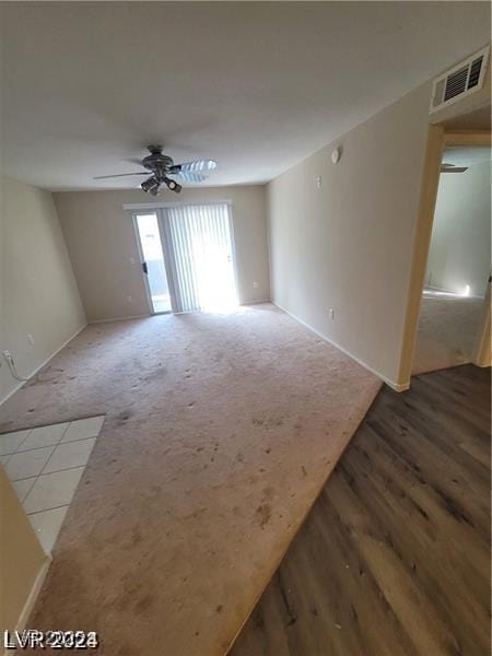 empty room featuring carpet floors, ceiling fan, and visible vents