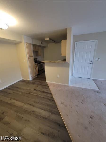 kitchen with a peninsula, electric range, wood finished floors, baseboards, and light countertops