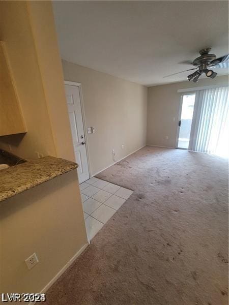 unfurnished living room featuring a ceiling fan and light colored carpet