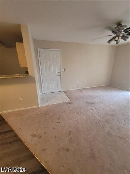 interior space featuring a ceiling fan, light carpet, and baseboards