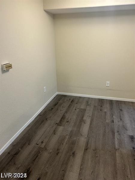 spare room with baseboards and dark wood finished floors