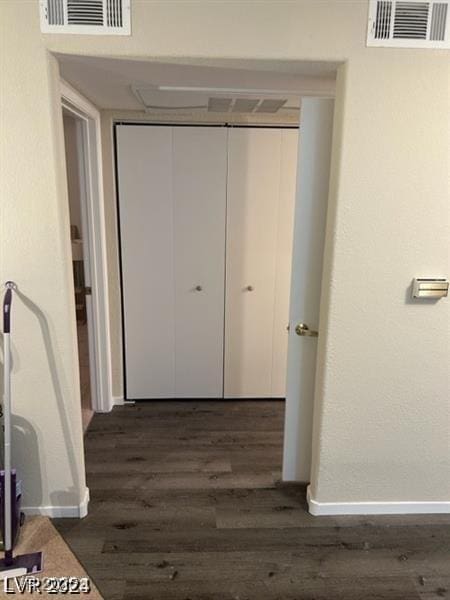 hallway with baseboards, visible vents, and dark wood-style flooring