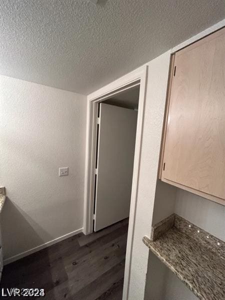 bathroom with a textured ceiling, baseboards, wood finished floors, and a textured wall