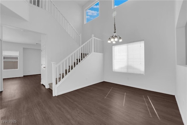 interior space featuring wood finished floors, a towering ceiling, and an inviting chandelier