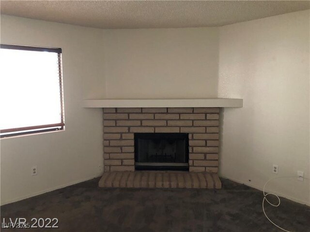 interior details with a textured ceiling, carpet floors, and a brick fireplace