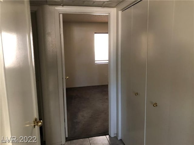 corridor with light tile patterned floors and light carpet