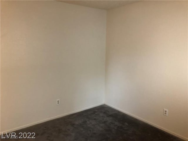 empty room with dark colored carpet and baseboards