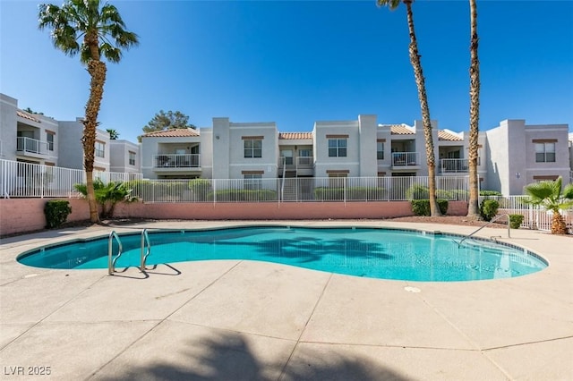 community pool featuring a patio, fence, and a residential view