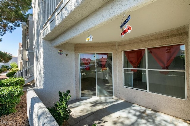 view of exterior entry featuring a patio and stucco siding