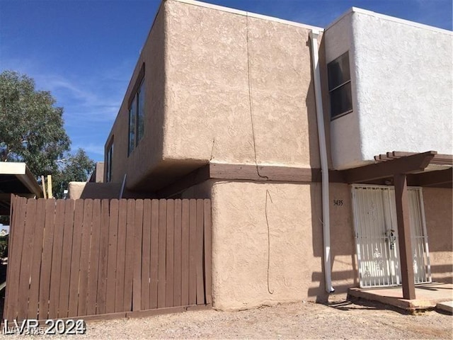 view of side of property with fence and stucco siding