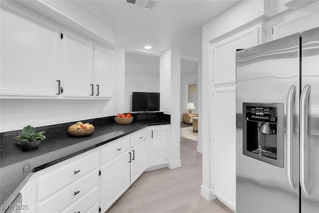 kitchen with recessed lighting, stainless steel refrigerator with ice dispenser, visible vents, and white cabinets