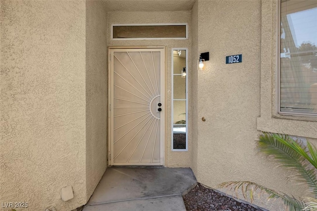 doorway to property featuring stucco siding