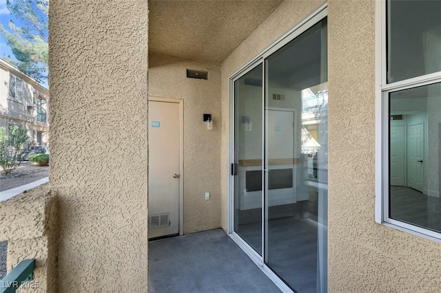 entrance to property featuring visible vents and stucco siding