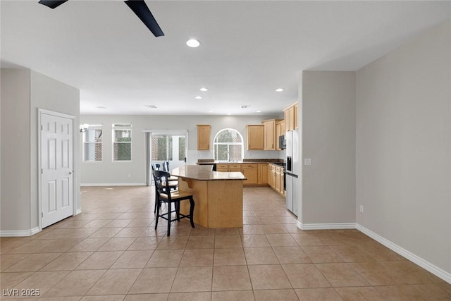 kitchen featuring light brown cabinetry, a center island, recessed lighting, and light tile patterned floors