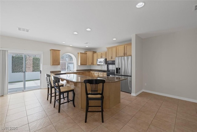 kitchen with a center island, light tile patterned floors, visible vents, appliances with stainless steel finishes, and a sink