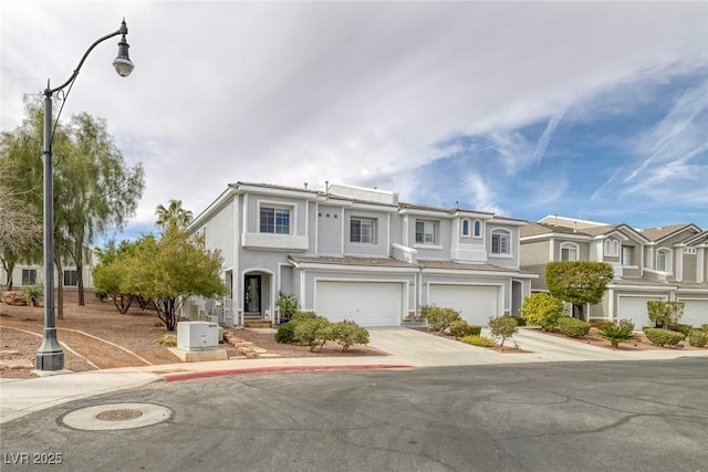 view of property featuring driveway, a garage, and stucco siding