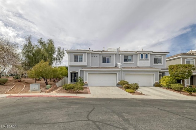 multi unit property with driveway, a garage, and stucco siding