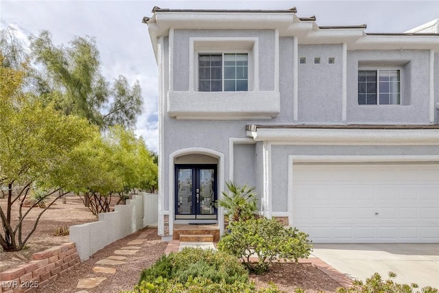 view of front of home featuring a garage, french doors, concrete driveway, and stucco siding