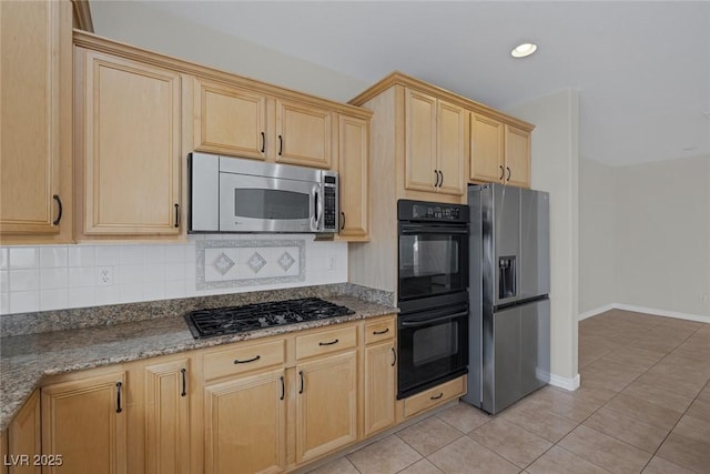 kitchen with stone counters, light tile patterned floors, tasteful backsplash, light brown cabinetry, and black appliances