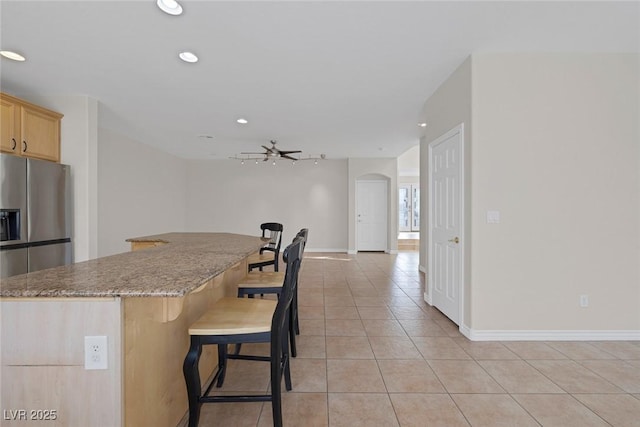 kitchen featuring arched walkways, a breakfast bar area, light tile patterned flooring, and recessed lighting