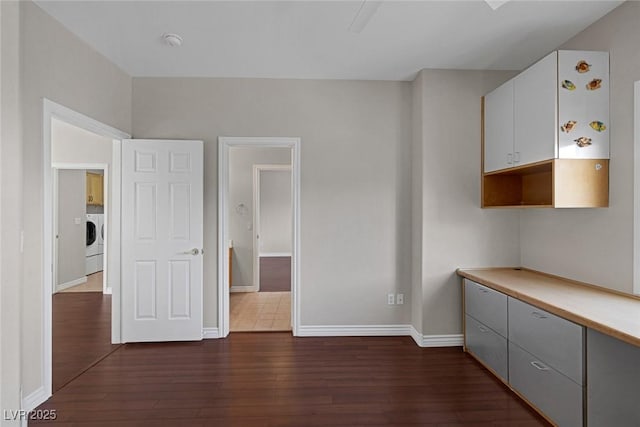 interior space featuring washer / clothes dryer, light countertops, gray cabinets, dark wood-type flooring, and baseboards