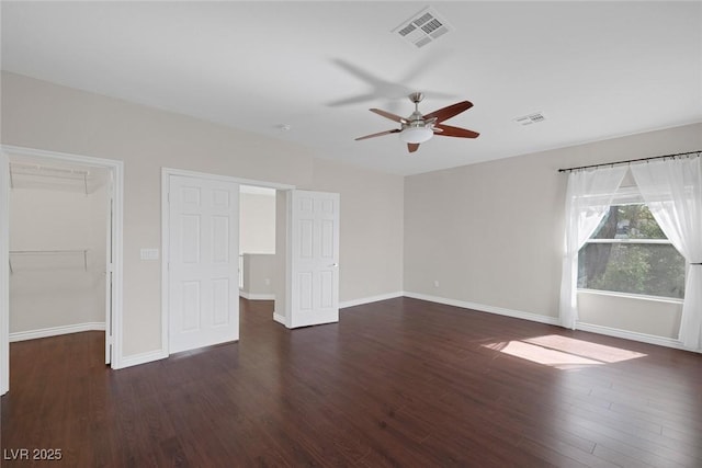 unfurnished bedroom featuring a walk in closet, visible vents, and wood finished floors