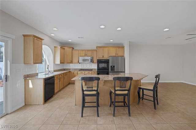 kitchen with a sink, a kitchen island, black appliances, and light tile patterned floors