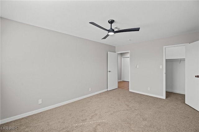 unfurnished bedroom with ceiling fan, carpet flooring, visible vents, baseboards, and a walk in closet