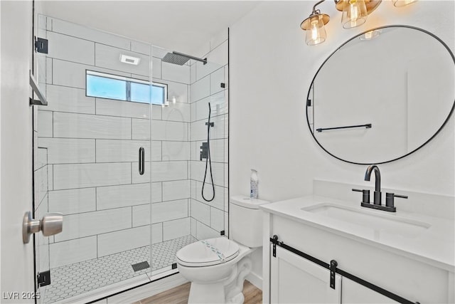 bathroom with toilet, a stall shower, wood finished floors, and vanity