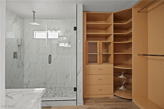 bathroom featuring a marble finish shower and wood finished floors