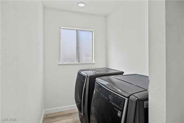 laundry area with laundry area, baseboards, washer and clothes dryer, and wood finished floors