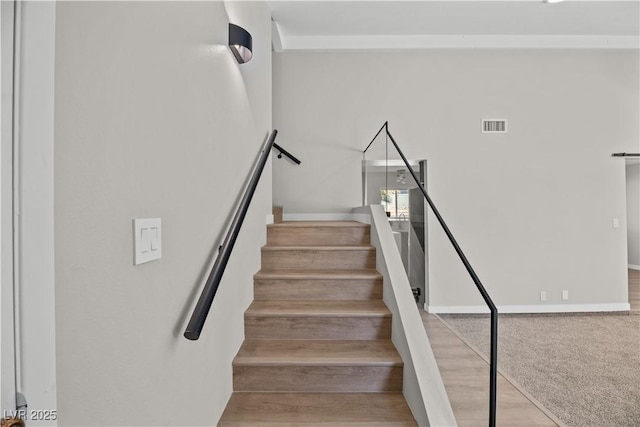 stairway with wood finished floors, visible vents, and baseboards