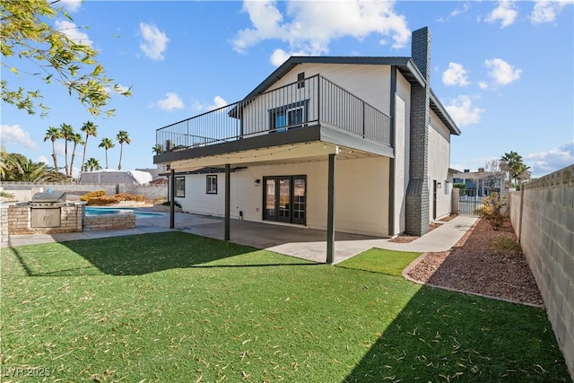 rear view of house with a fenced in pool, a fenced backyard, a chimney, a yard, and a patio area