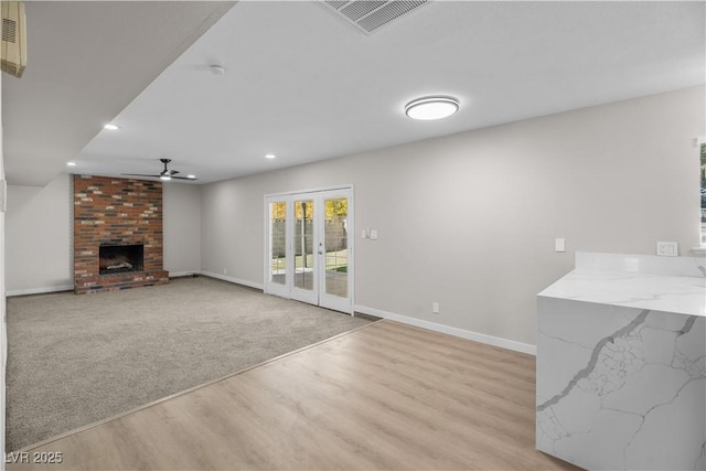 unfurnished living room featuring a fireplace, visible vents, light wood-style floors, a ceiling fan, and baseboards