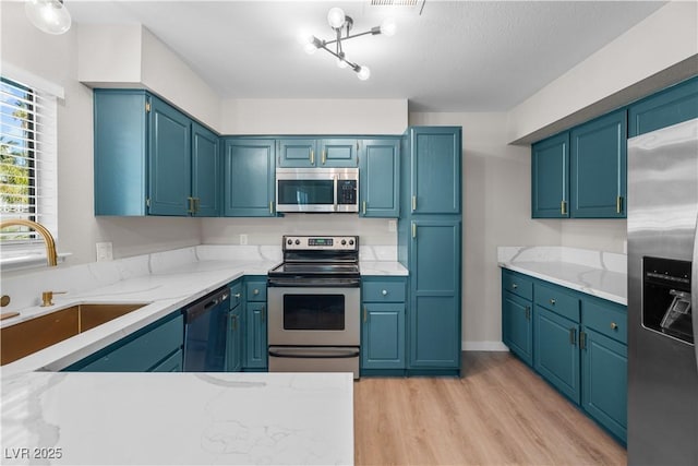 kitchen featuring a sink, visible vents, appliances with stainless steel finishes, light wood-type flooring, and light stone countertops