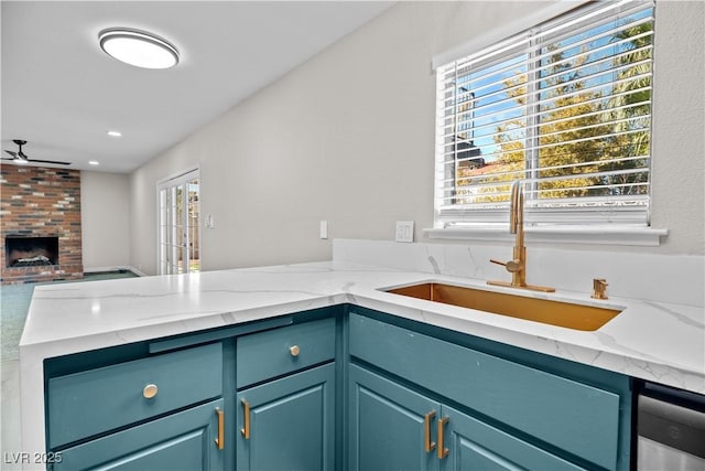 kitchen featuring open floor plan, a sink, a peninsula, and light stone countertops