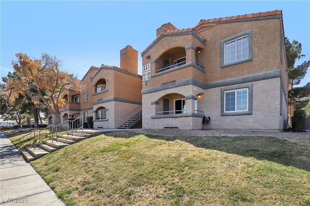 mediterranean / spanish-style house featuring a front lawn, a balcony, and stucco siding