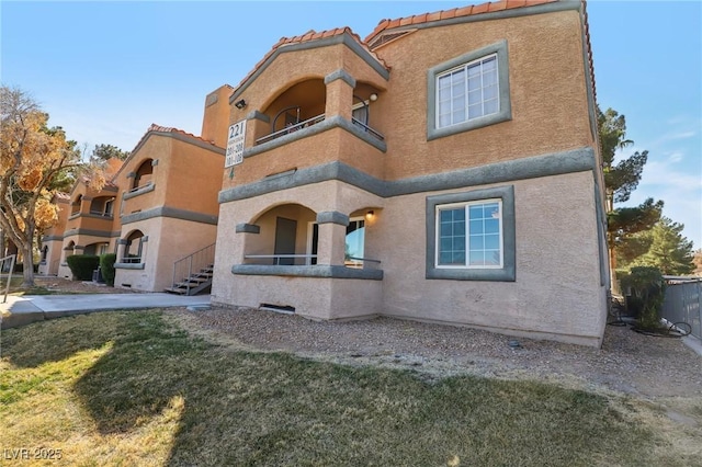 view of front of home featuring a balcony, a tile roof, and stucco siding