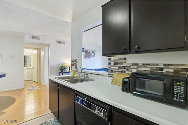 kitchen featuring black appliances, light countertops, a sink, and visible vents