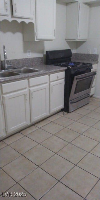 kitchen with stainless steel gas range, white cabinetry, a sink, and light tile patterned flooring