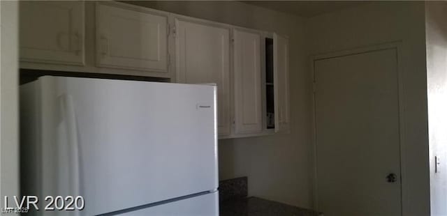 kitchen with freestanding refrigerator and white cabinetry