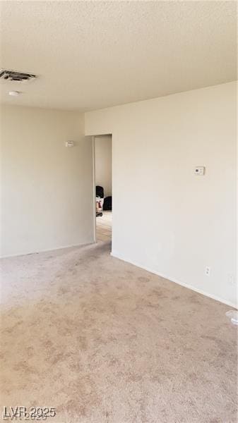 spare room with light carpet, a textured ceiling, and visible vents