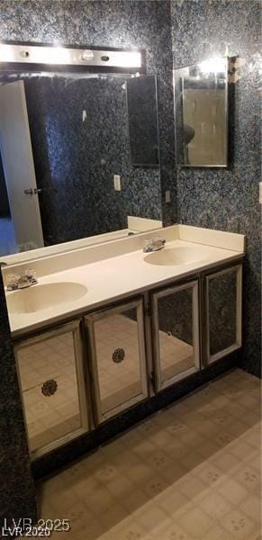 bathroom with double vanity, a sink, and wallpapered walls