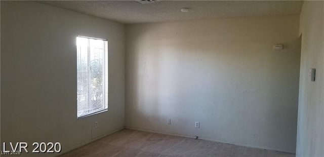 unfurnished room featuring a textured ceiling and light colored carpet